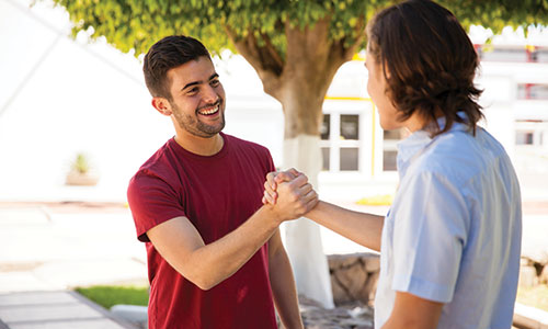 Two young men greeting one another.