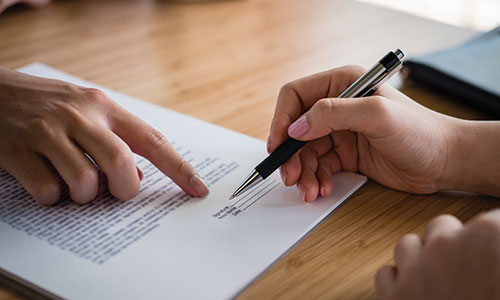 Person instructing another where to sign document.