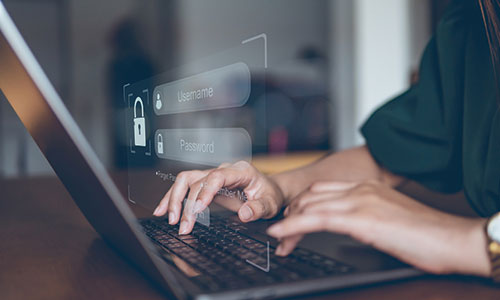 Person typing on laptop keyboard with overlay showing input boxes for username and password.