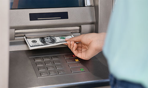 Person pulling deposited money out of ATM machine.